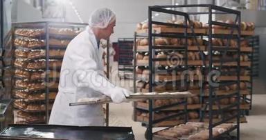 专业的面包师<strong>老头</strong>长得漂亮，拿着装满生面包的大托盘，装在架子上准备